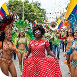 Bailarinas con trajes coloridos y banderas de Colombia celebran el Carnaval de Barranquilla en la calle.