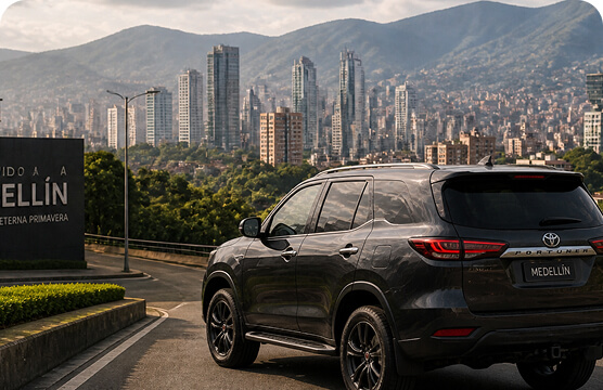 SUV driving on a road with the Medellín skyline and mountains in the background.