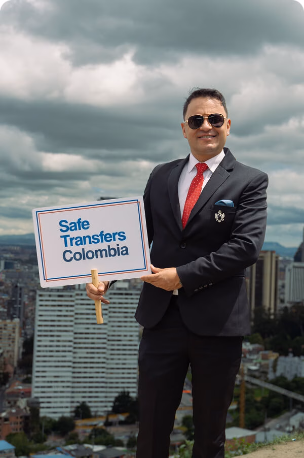 DSC02303 2 Man in a suit holding a Safe Transfers Colombia sign against the Bogotá skyline.