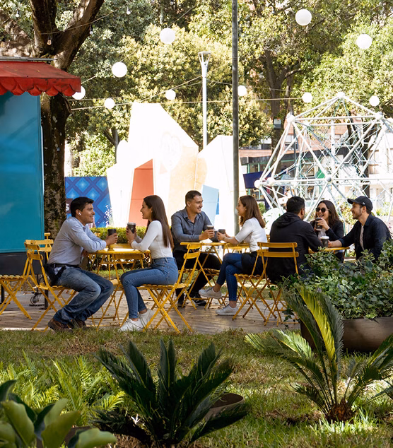 Group of friends chatting at an outdoor café with string lights overhead.