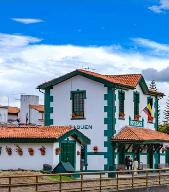 Historic Usaquén train station with traditional architecture and the Colombian flag.