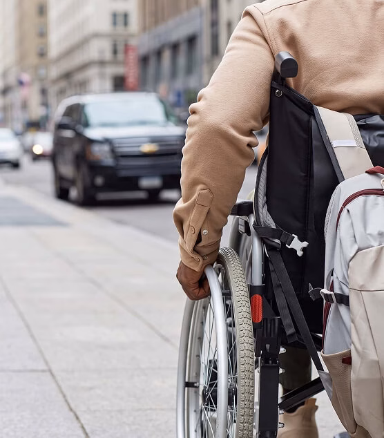 Person in a wheelchair moving along a city sidewalk.