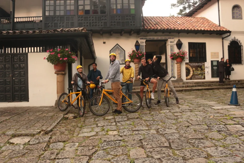 Orange tour bikes parked on cobblestones outside a white colonial house in Bogota