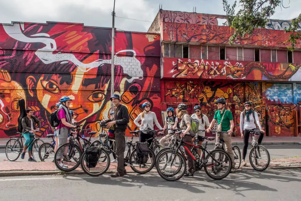 A cycling group stopped in front of a large street-art mural in Bogota A cycling group stopped in front of a large street-art mural in Bogota