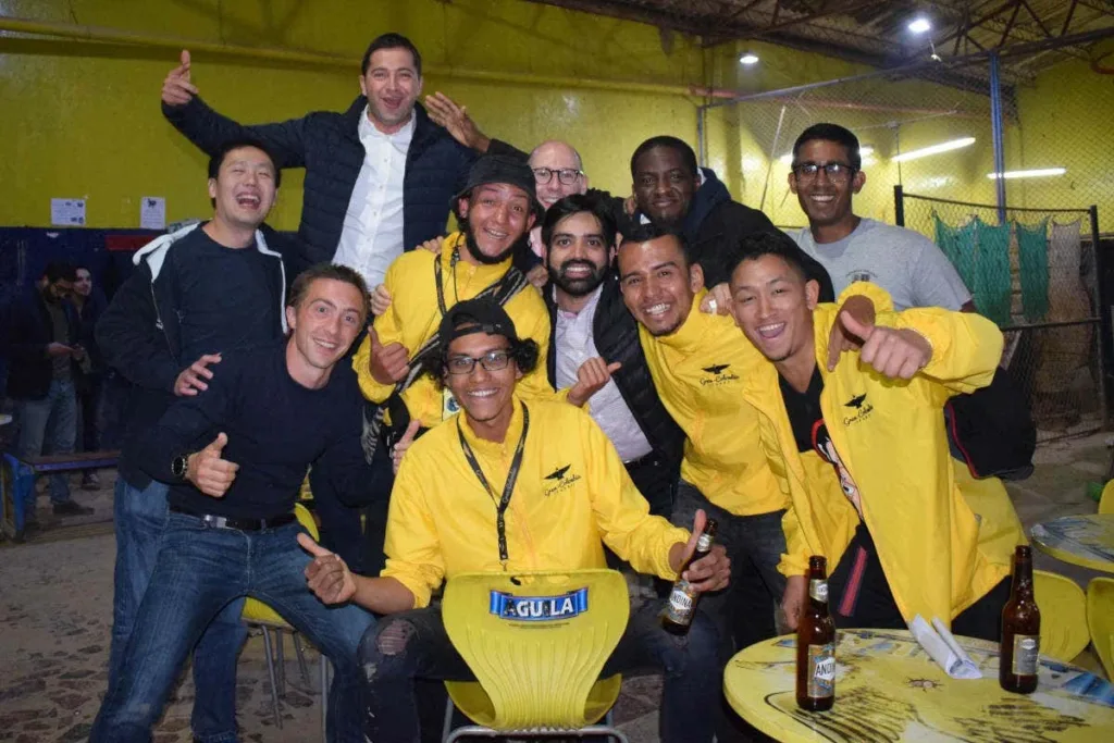 A group of travelers and hosts celebrating with beers after a tejo game