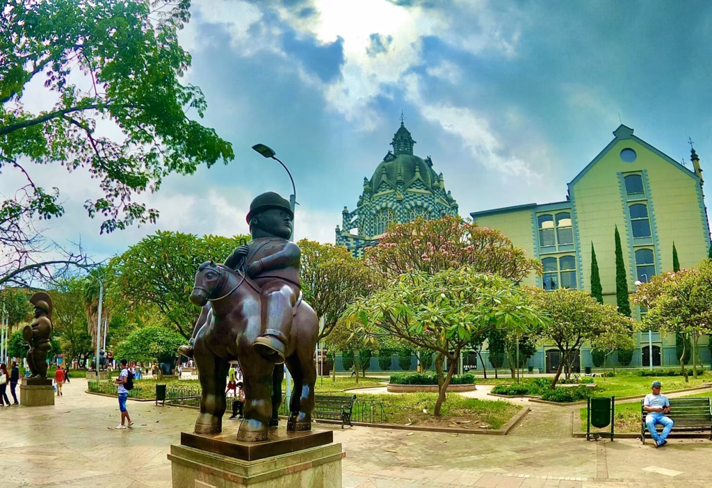 Bronze equestrian statue in a green plaza with the green dome of the Palacio de la Cultura behind
