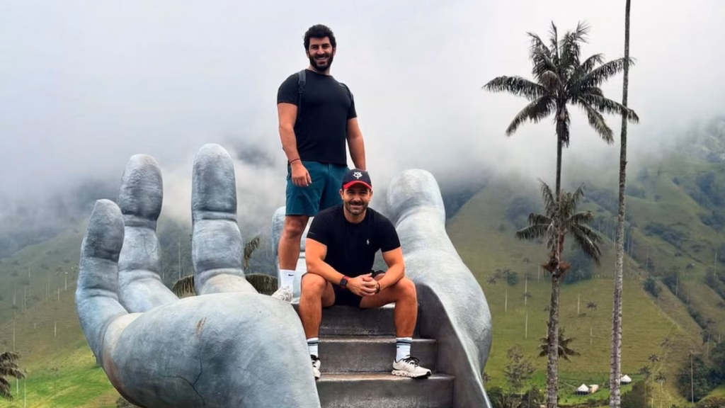 Viajeros en una gran escultura de mano con palmas de cera detrás