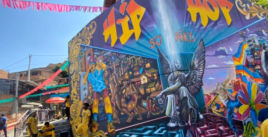 Large winged mural above a Comuna 13 street with parasols and a painted beam of light