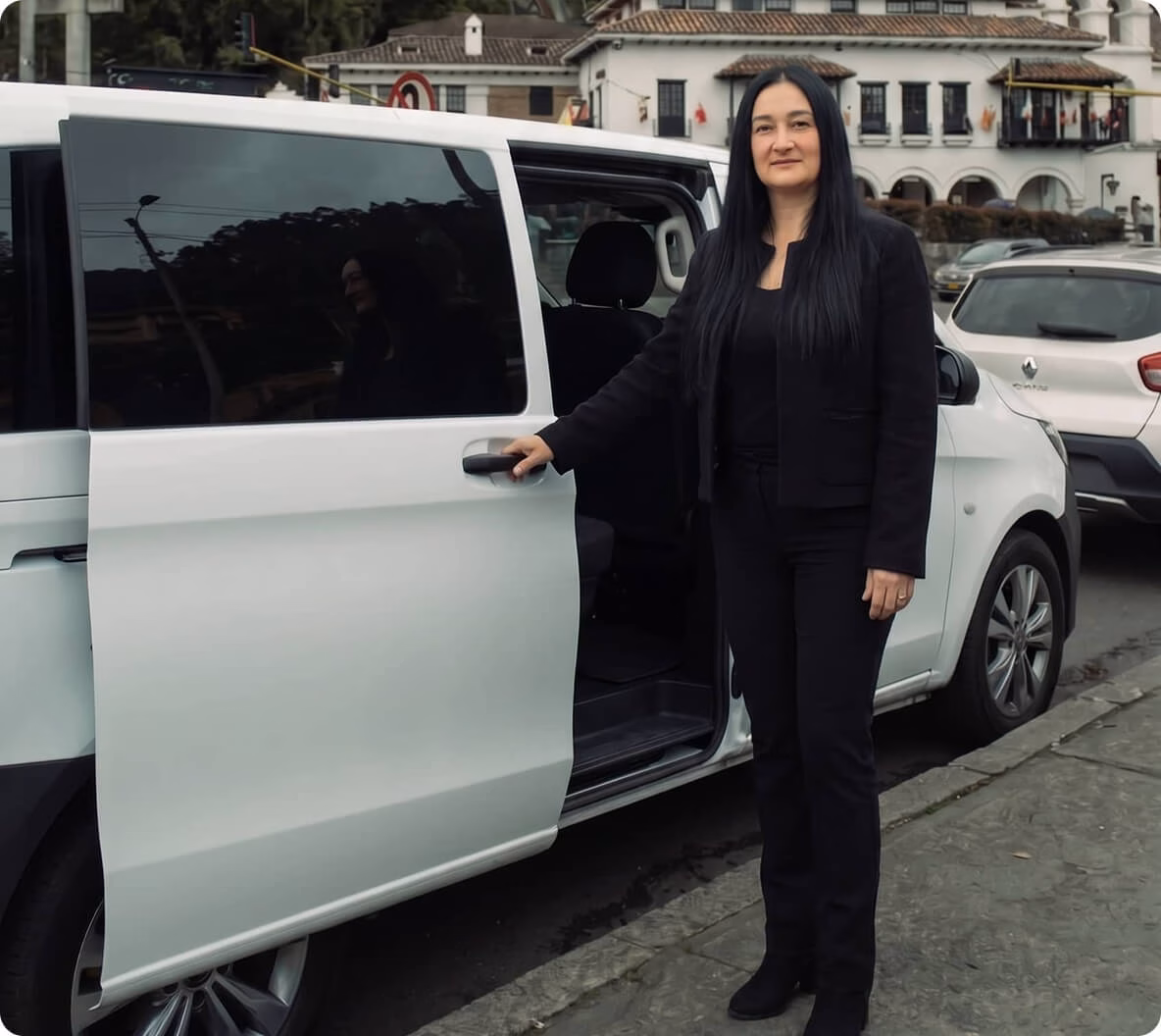 imagen-conductora-mujer Mujer conductora parada junto a una furgoneta blanca, con la colina de Monserrate en el fondo.