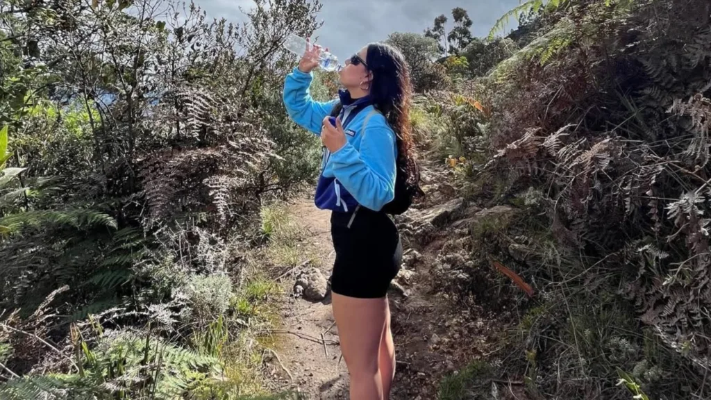 A hiker drinking water on the Las Moyas trail through Andean scrub