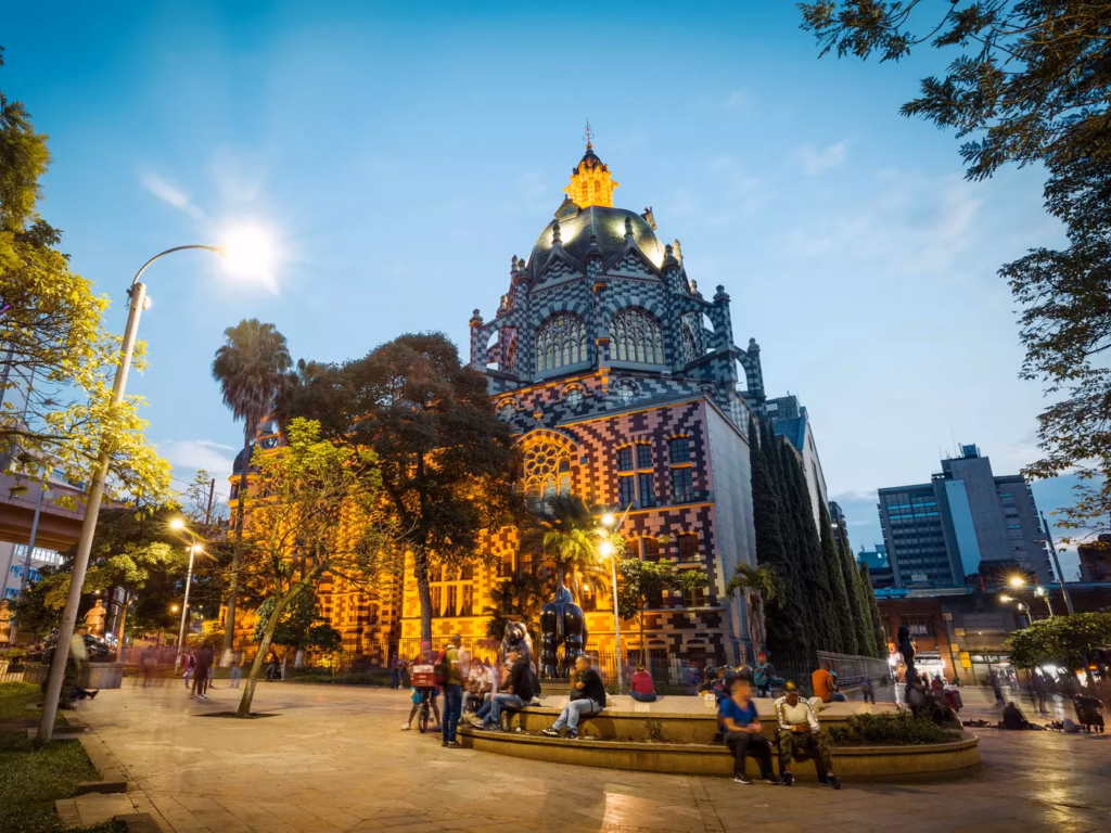 Palacio de la Cultura Rafael Uribe Uribe al anochecer, su fachada ajedrezada iluminada sobre las palmeras en el centro de Medellín