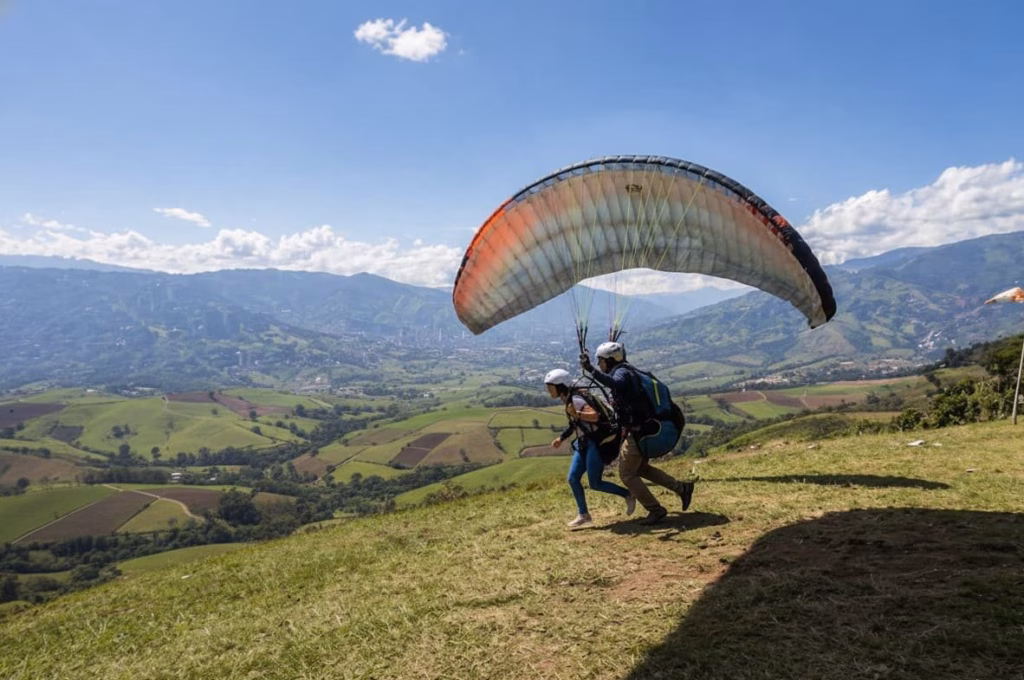Un parapente en tándem preparándose para despegar del filo sobre el valle del Quindío