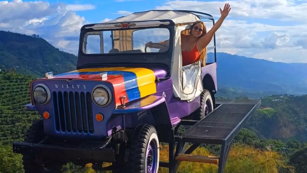 Un viajero saludando desde un jeep Willys en un mirador sobre el Quindío