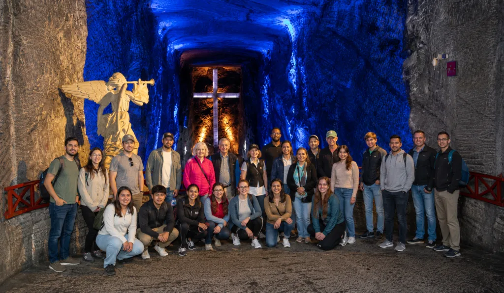 A tour group in front of the illuminated cross inside the Zipaquira Salt Cathedral