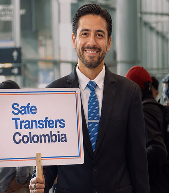 Man holding a Safe Transfers Colombia sign in the airport terminal.