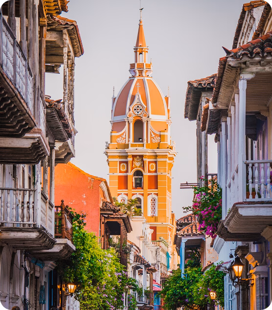 Colonial street in Cartagena with colorful balconies and the cathedral tower in the background.