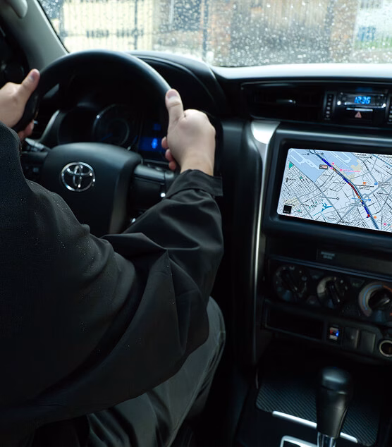 View from the driver's seat showing hands on the wheel and the navigation screen.