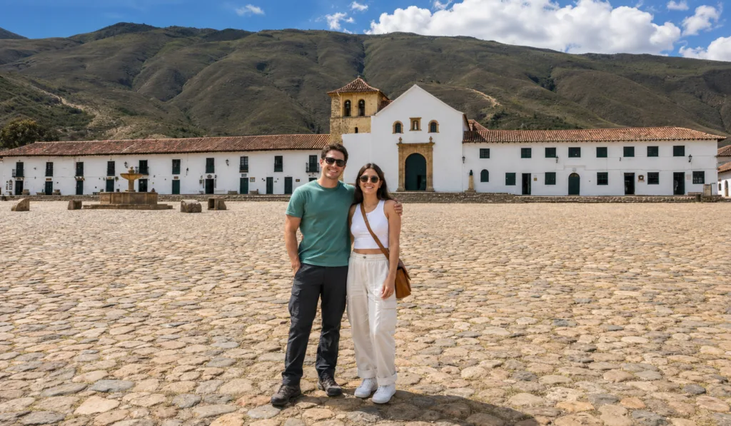 A couple on the cobbled Plaza Mayor of Villa de Leyva in front of the white church A couple on the cobbled Plaza Mayor of Villa de Leyva in front of the white church