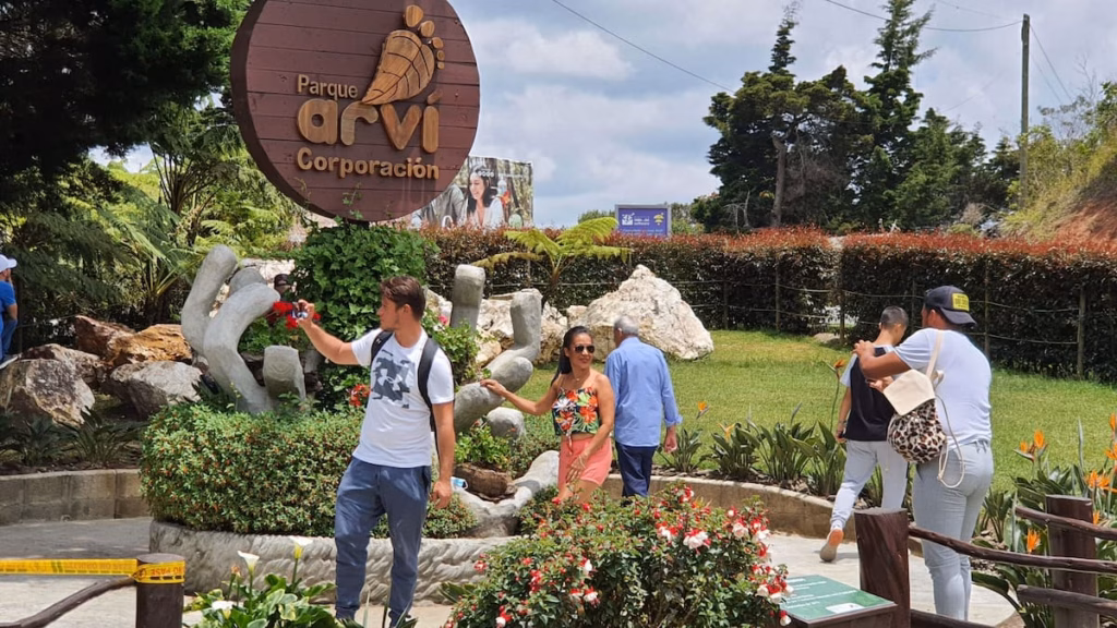 Visitors taking photographs by the Arví Park entrance sign and its rock garden