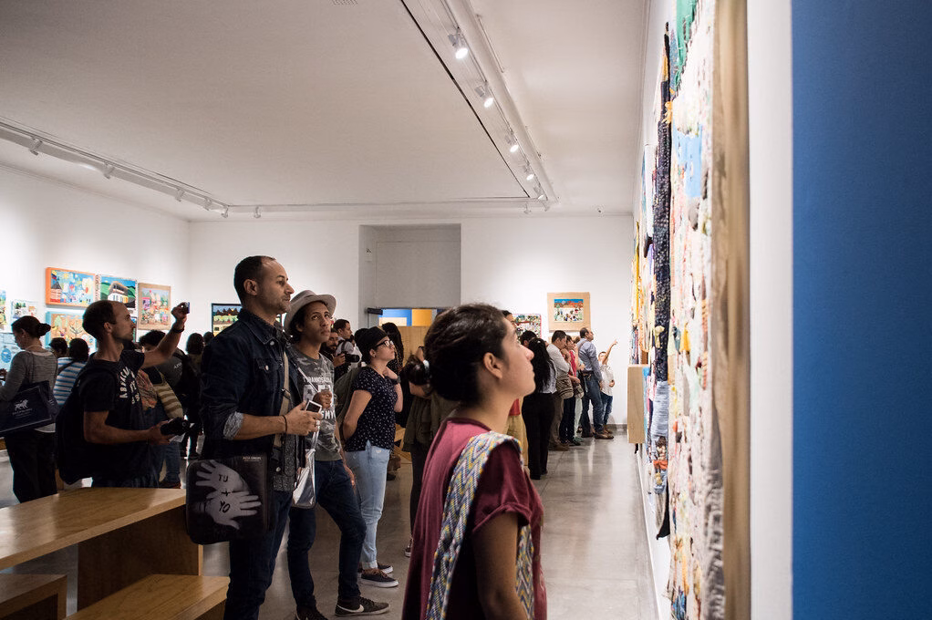 Visitors looking at wall exhibits in a bright museum gallery in Medellín