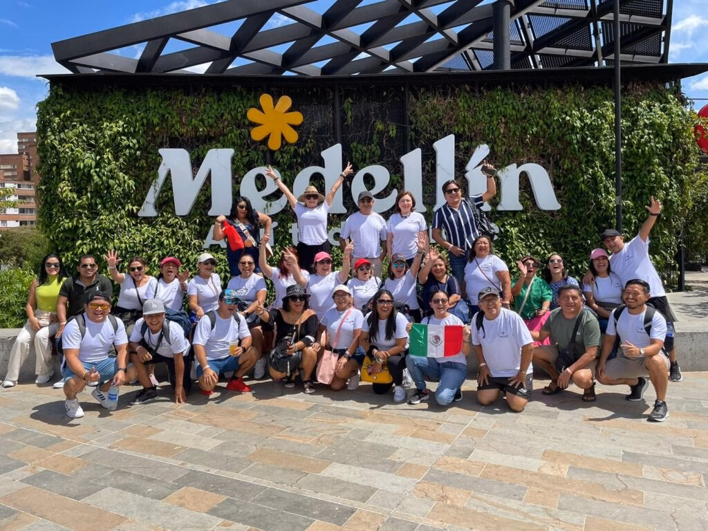 Large walking tour group posing under the white Medellín letters