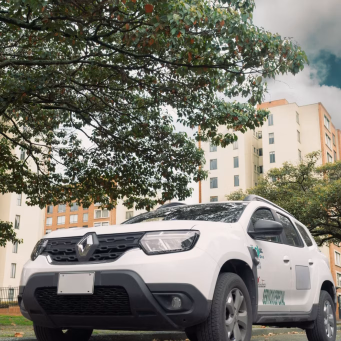 white-renault-duster-front-three-quarter-low-angle-under-tree-apartments-daytime White Renault Duster private transfer car in Bogota